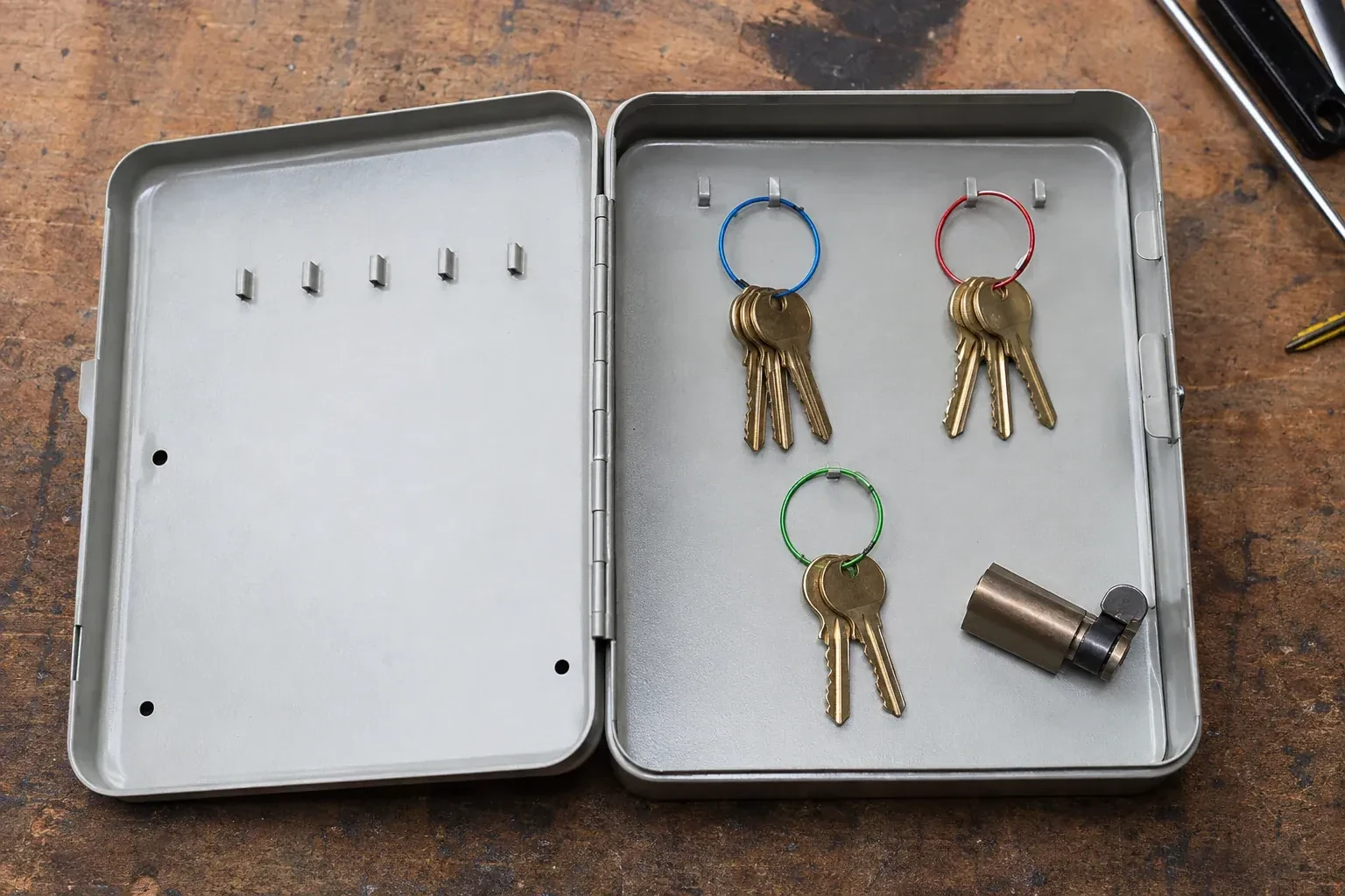 Three groups of keys on colored rings in an open metal key cabinet. — Master Key System Design, Oakville