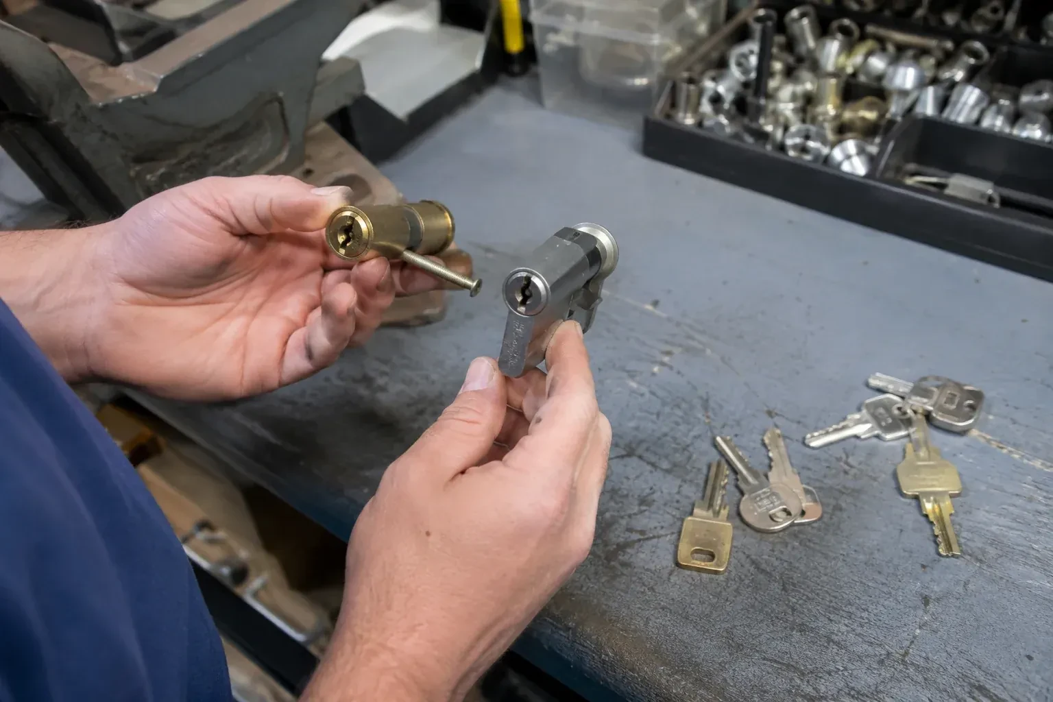 Hands comparing detached lock cylinders beside loose keys on a workbench. — Broken Key Extraction, Oakville